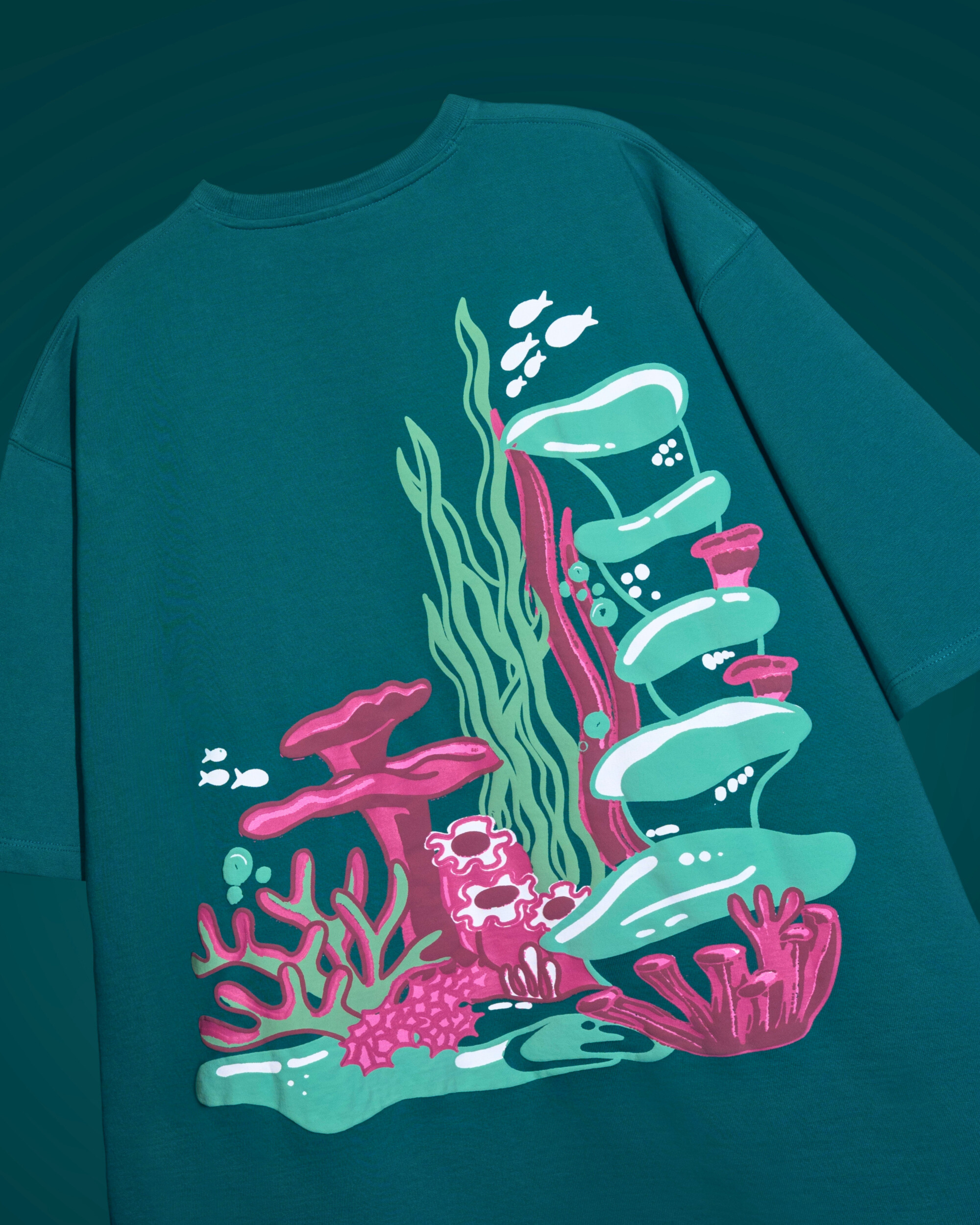 Teal t shirt with colorful coral reef design on a dark teal background